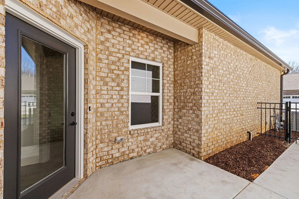 Brick exterior with a glass door and window, featuring a small patio area by Pratt Home Builders in Chattanooga TN.