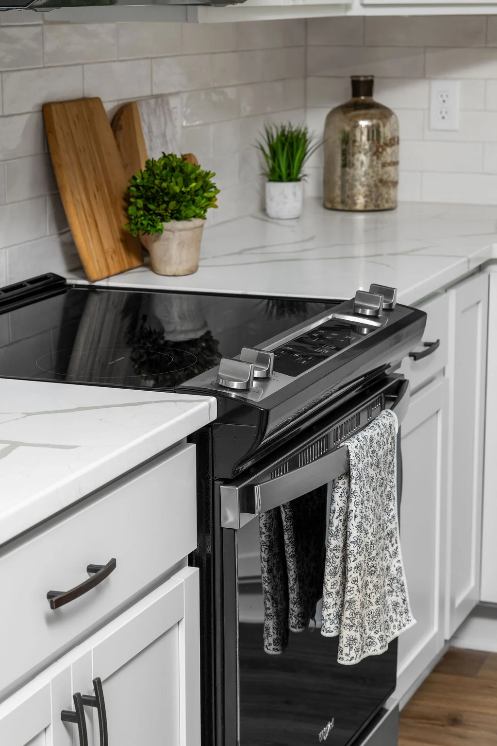New Home Chattanooga TN. Modern kitchen with black stove, floral towel, white countertops, and decorative plants. Designed by Pratt Home Builders.
