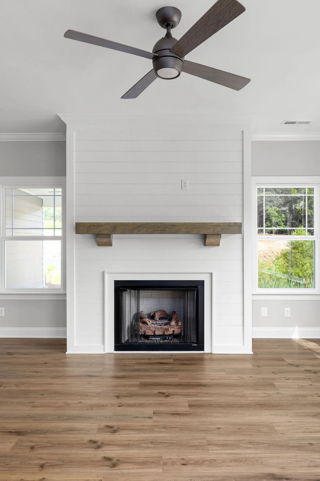 New Home Chattanooga TN. Modern living room with a ceiling fan, shiplap fireplace, and wood floors, designed by Pratt Home Builders.