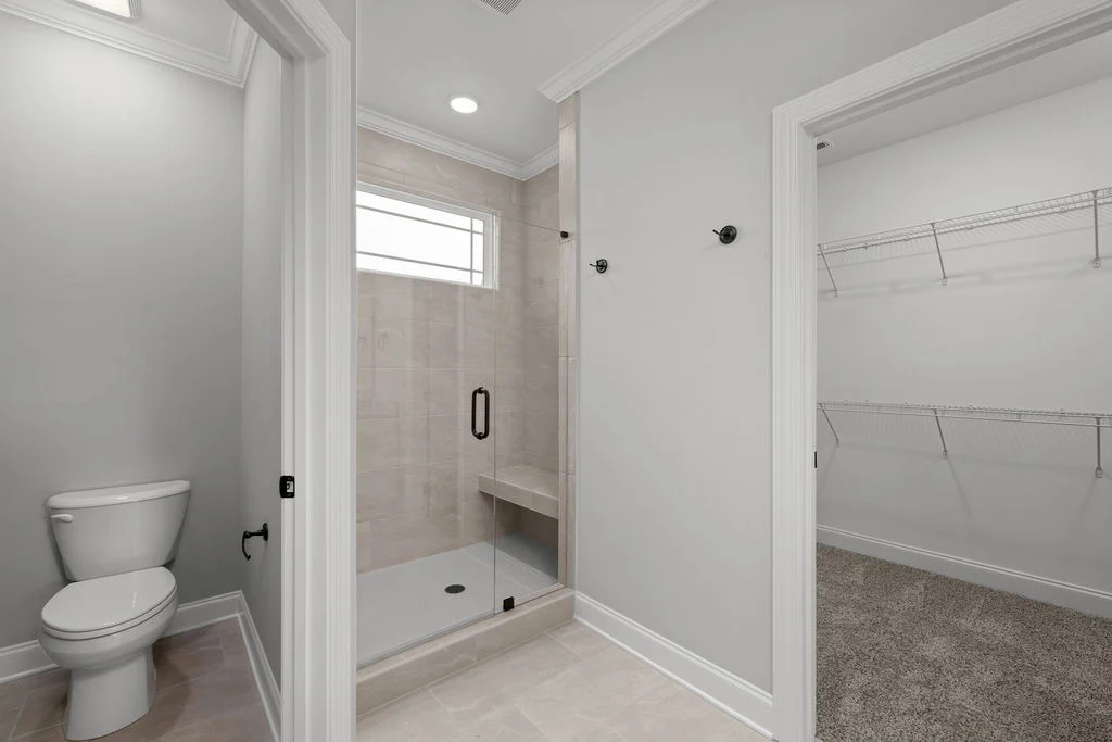 New Home Chattanooga TN. Modern bathroom by Pratt Home Builders, featuring a glass-enclosed shower, toilet, and adjacent walk-in closet with wire shelving.