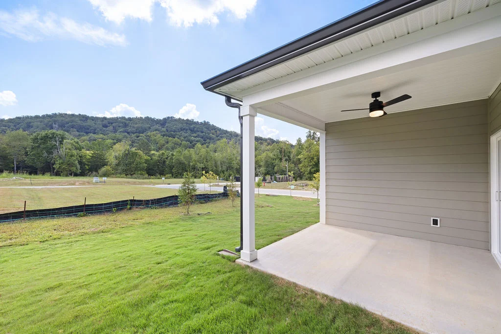 Covered patio with ceiling fan overlooking a grassy yard and distant hills, built by Pratt Home Builders in Chattanooga TN.