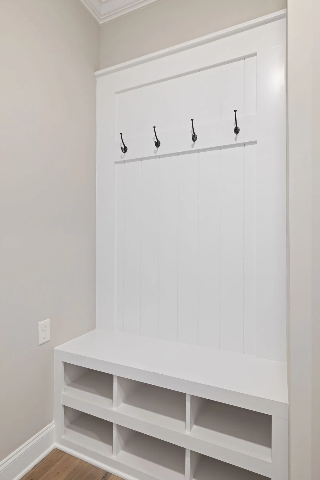 White entryway bench with four hooks and cubby storage, designed by Pratt Home Builders in Chattanooga TN.