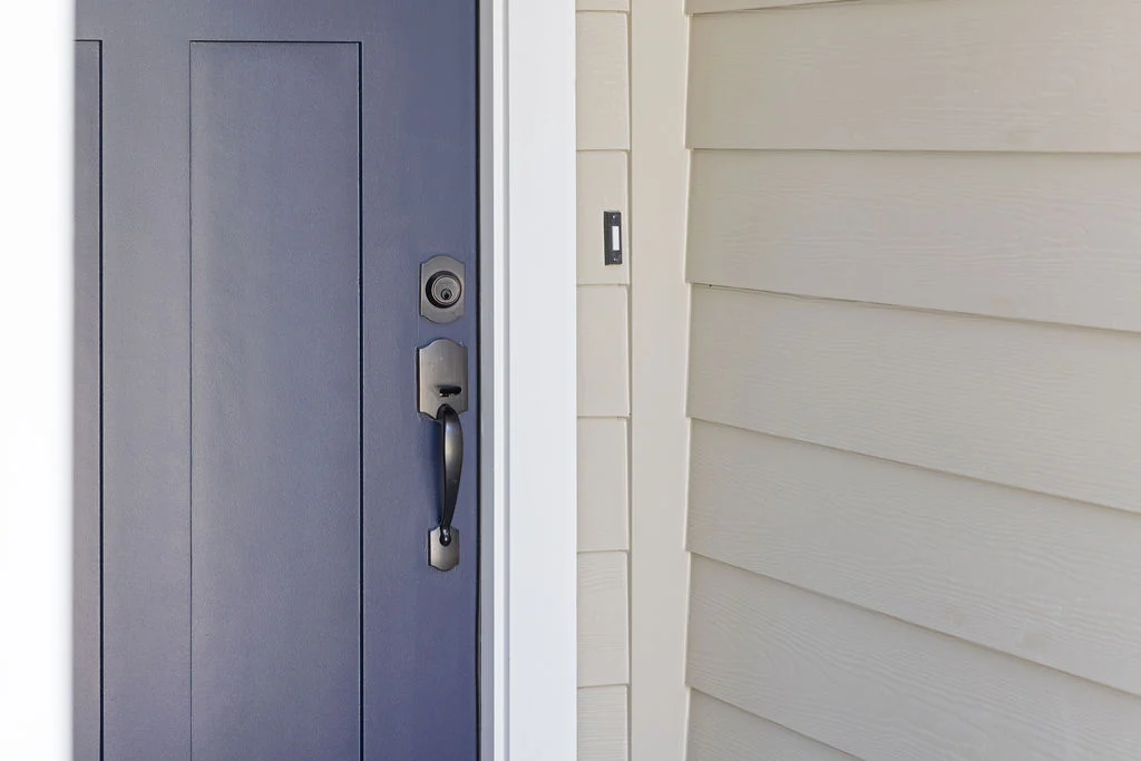 Navy blue front door with sleek handle next to beige siding, showcasing Pratt Home Builders in Chattanooga TN.