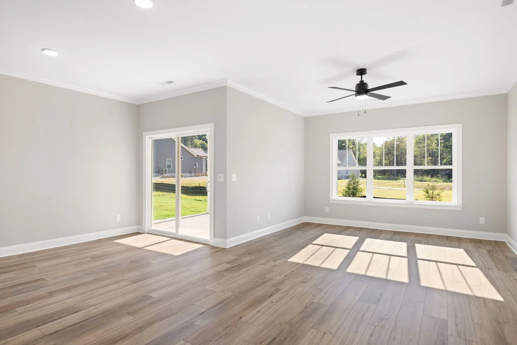 Spacious living room with large windows, sliding door, and ceiling fan, showcasing Pratt Home Builders design in Chattanooga TN.