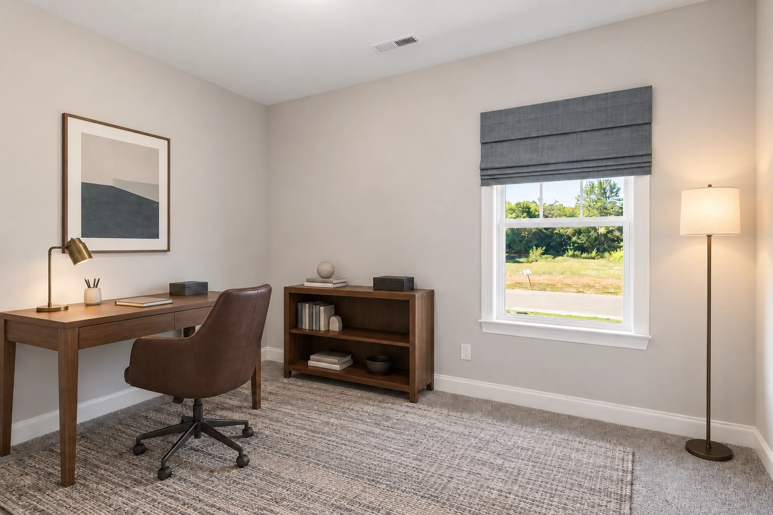 Minimalist home office with brown desk, leather chair, and bookshelf under window, crafted by Pratt Home Builders in Chattanooga TN.