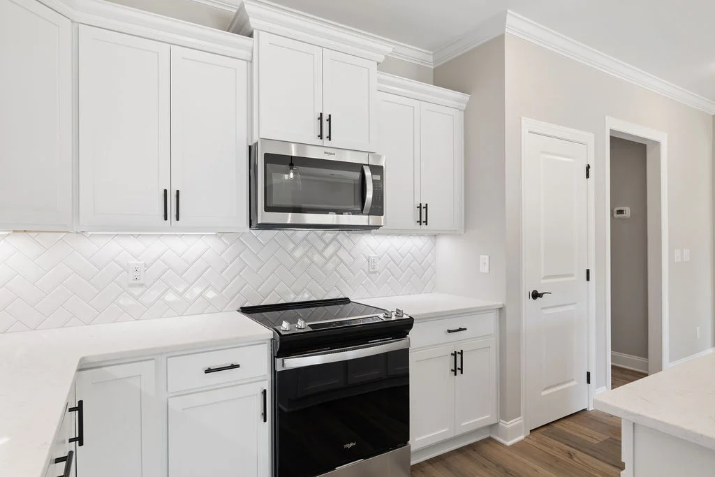 Modern kitchen with white cabinets, stainless steel appliances, herringbone backsplash, and sleek design by Pratt Home Builders in Chattanooga TN.