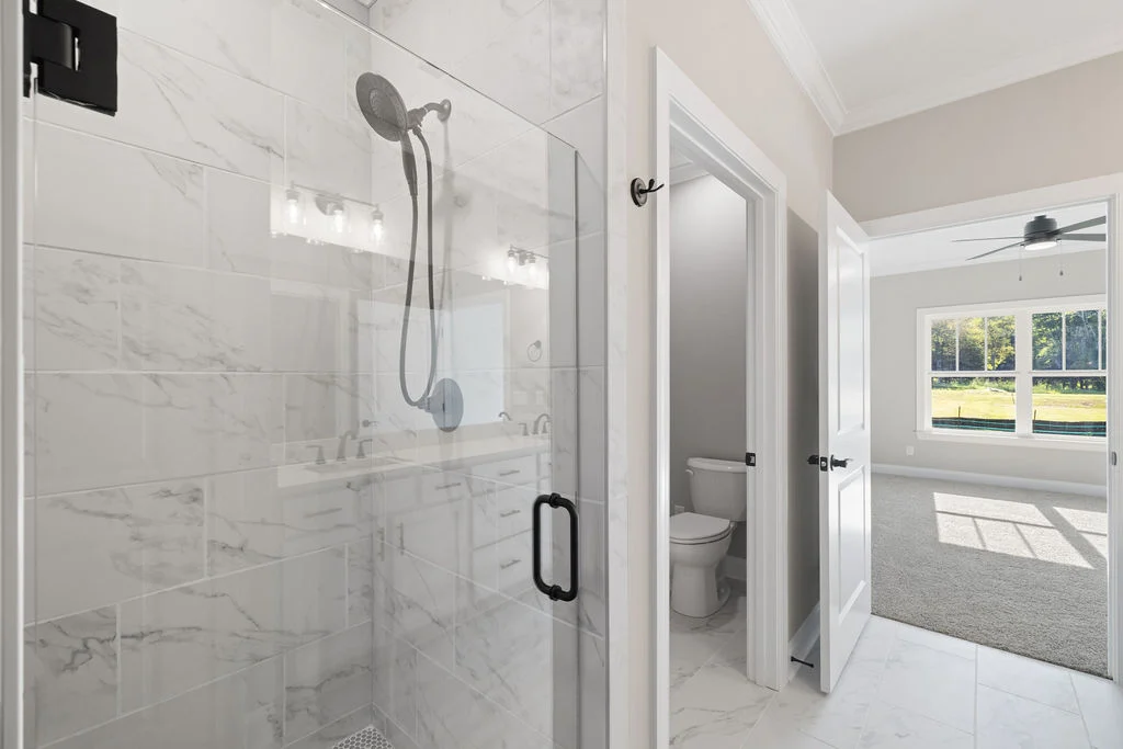 Modern bathroom with glass shower, adjacent toilet, and a bright room view by Pratt Home Builders in Chattanooga TN.