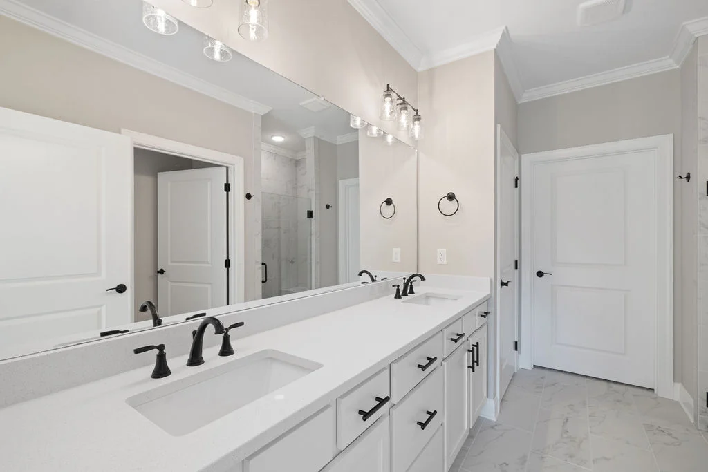 Elegant bathroom with double vanity, black fixtures, and large mirror. Designed by Pratt Home Builders in Chattanooga TN.