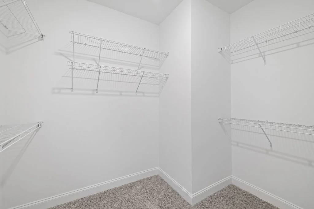 Walk-in closet with white wire shelving on walls, featuring spacious storage by Pratt Home Builders in Chattanooga TN.