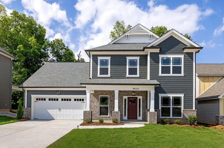 Modern two-story house with gray siding, manicured lawn, and spacious driveway by Pratt Home Builders in Chattanooga, TN.