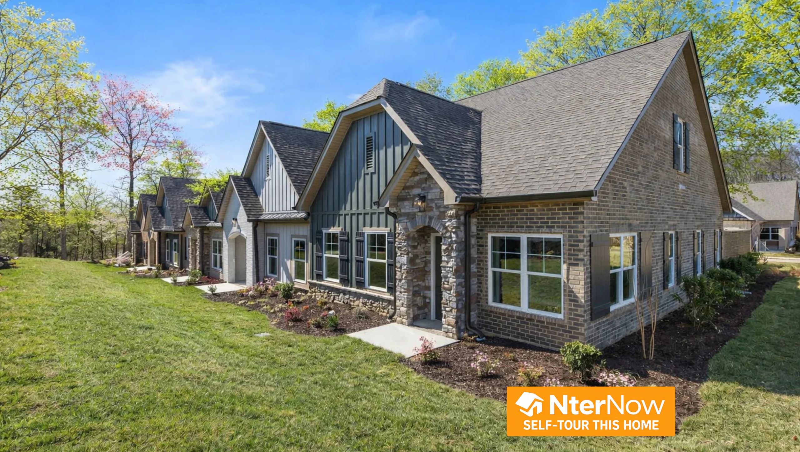 Modern brick homes with gable roofs and landscaped lawns by Pratt Home Builders in Chattanooga TN under a clear blue sky.