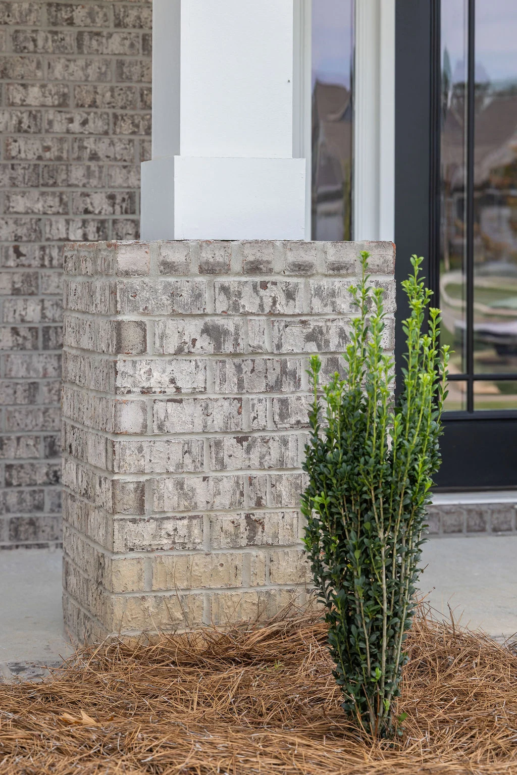 Brick porch pillar with a small shrub in mulch, showcasing Pratt Home Builders' craftsmanship in Chattanooga TN.