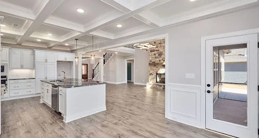 Spacious, modern kitchen and living area with coffered ceilings, large island, and hardwood floors by Pratt Home Builders in Chattanooga TN.