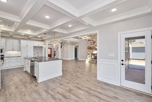 Spacious, modern kitchen and living area with coffered ceilings, large island, and hardwood floors by Pratt Home Builders in Chattanooga TN.