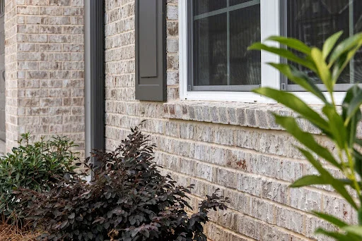 unnamed (2) Brick exterior with window, shutters, and shrubbery, showcasing a home by Pratt Home Builders in Chattanooga TN.