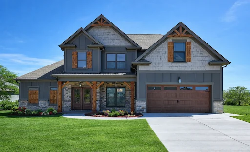 Two-story house with gabled roof, stone accents, and wood shutters. Built by Pratt Home Builders in Chattanooga TN. Lush lawn and driveway.