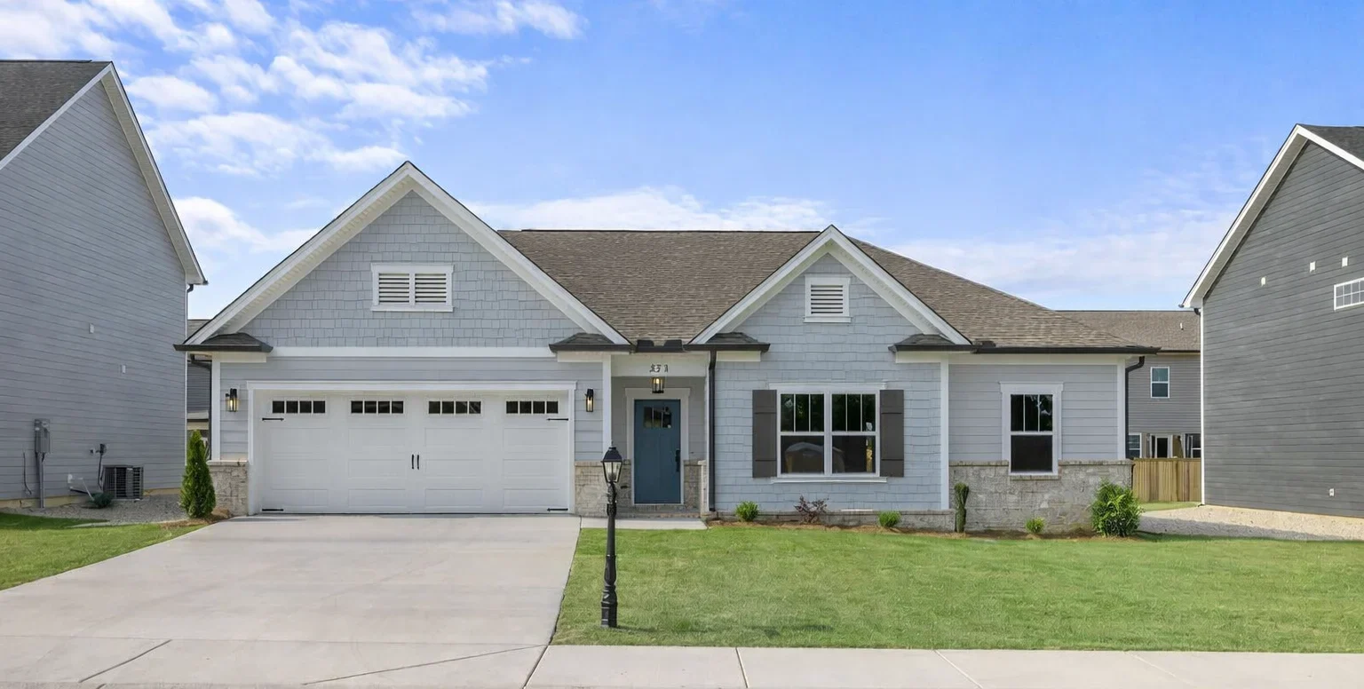 Single-story house with gray siding, white garage, and manicured lawn. Built by Pratt Home Builders in Chattanooga TN.