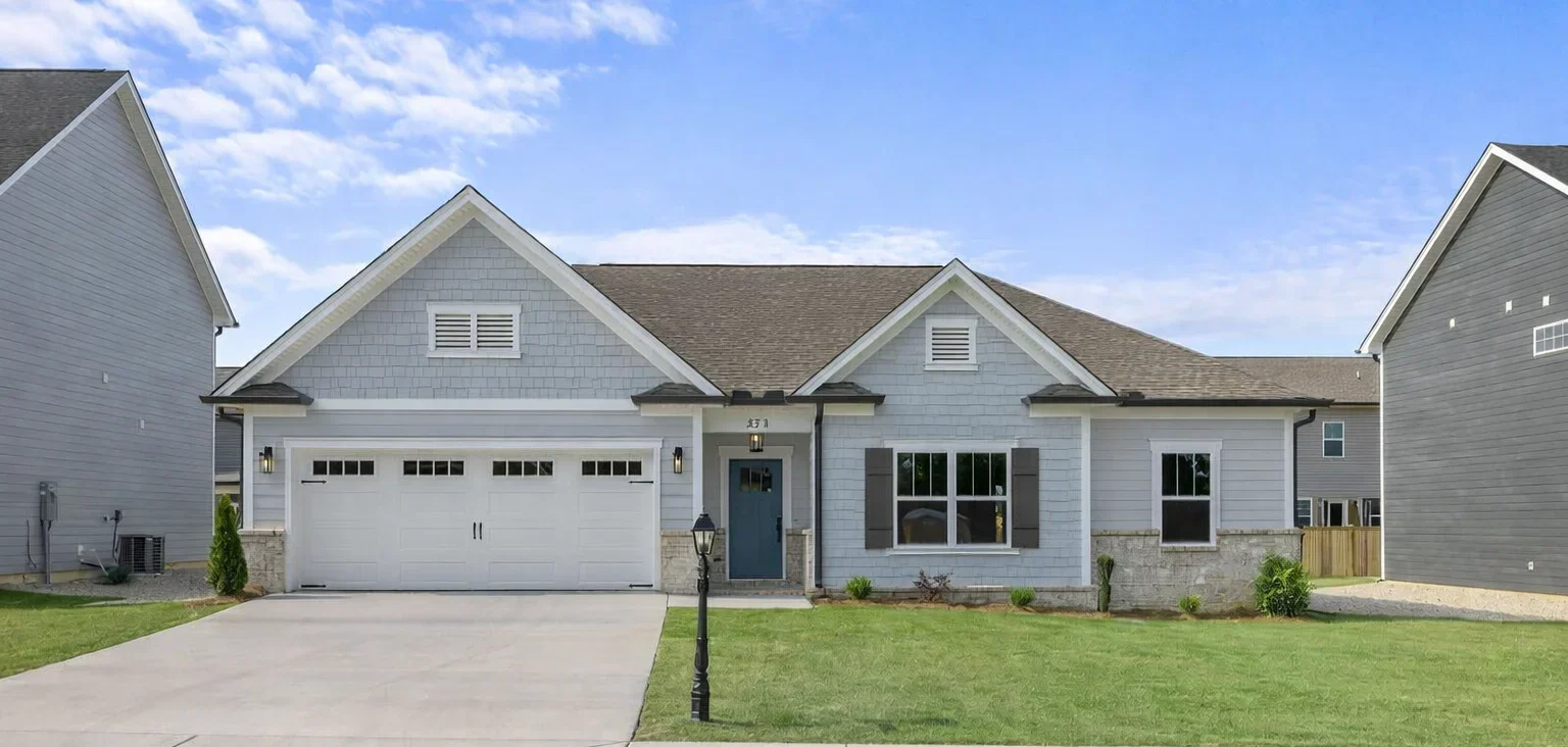 Single-story house with gray siding, white garage, and manicured lawn. Built by Pratt Home Builders in Chattanooga TN.