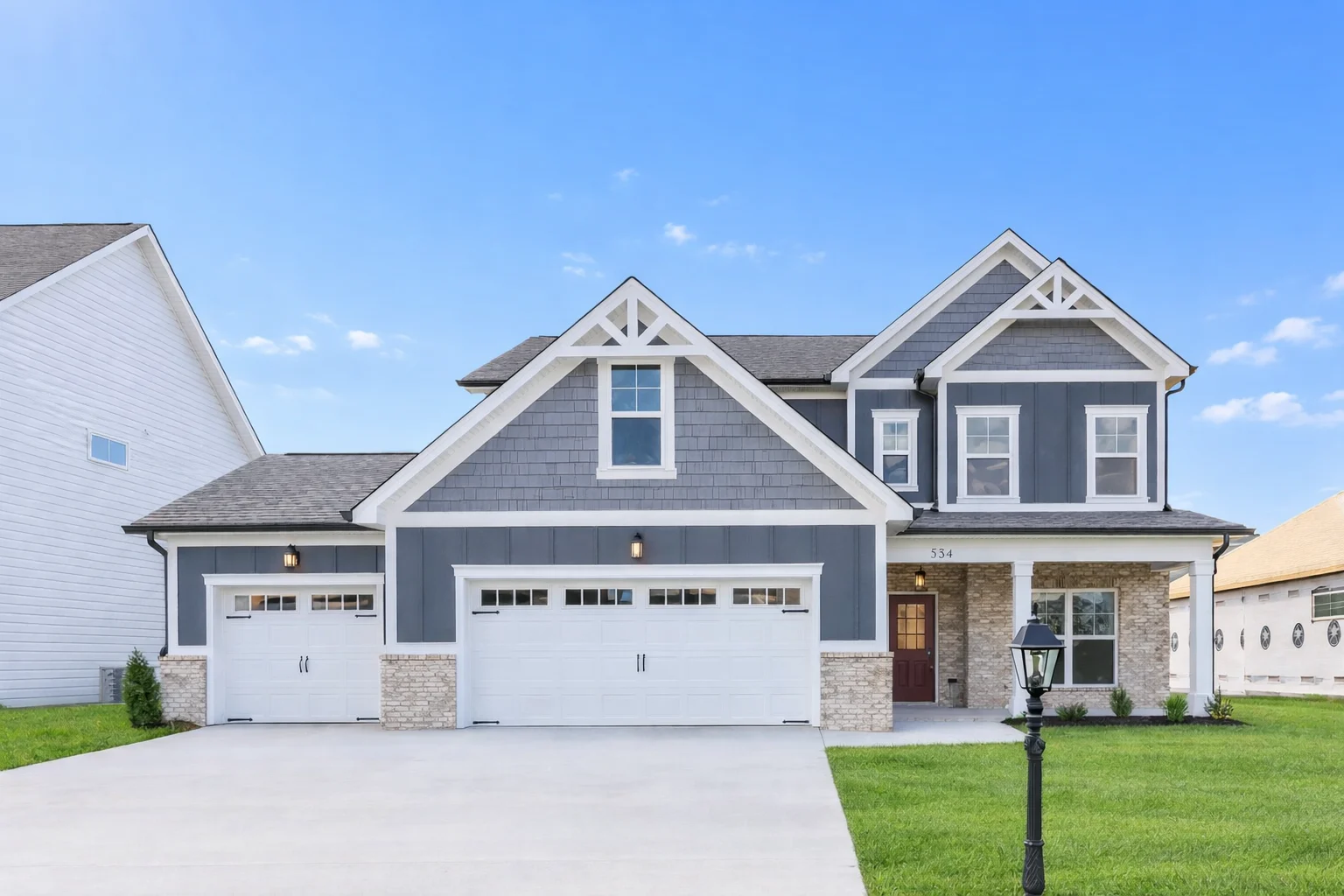 Two-story gray and white house with a three-car garage, built by Pratt Home Builders in Chattanooga, TN, against a clear blue sky.