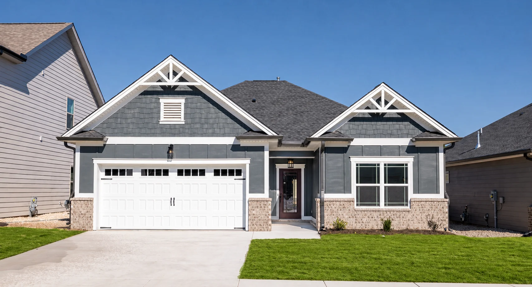Modern suburban home with gray siding, white trim, and a gabled roof by Pratt Home Builders in Chattanooga TN. Lush green lawn in front.