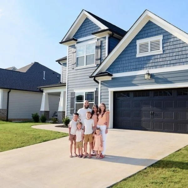 Family stands on driveway of a modern two-story house by Pratt Home Builders in Chattanooga TN, showcasing a well-maintained lawn.
