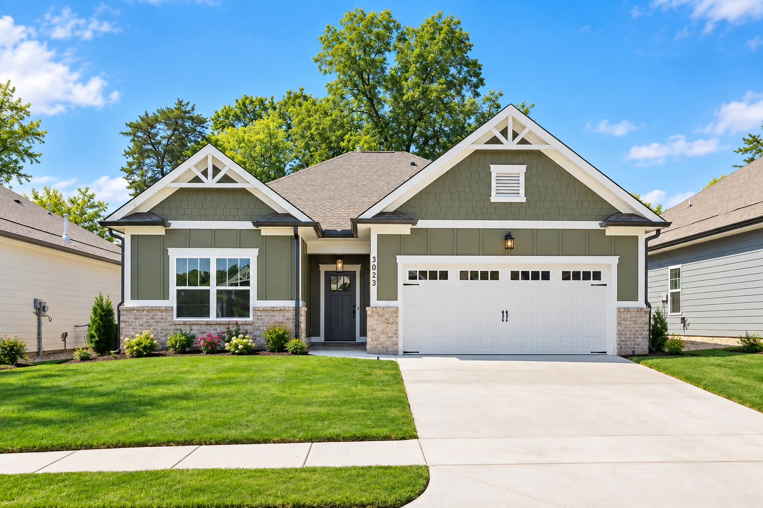 Modern single-story home with green siding, large garage, and manicured lawn, built by Pratt Home Builders in Chattanooga, TN.