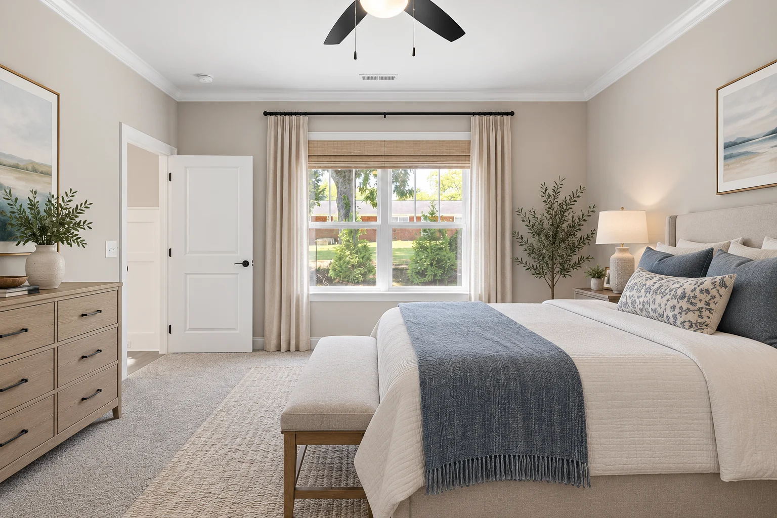Elegant bedroom by Pratt Home Builders in Chattanooga TN, featuring neutral decor, large window, and cozy bedding with blue accents.