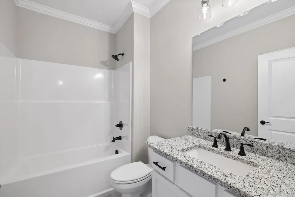 Bathroom with granite countertop, single sink, black fixtures, and a bathtub. Designed by Pratt Home Builders in Chattanooga TN.