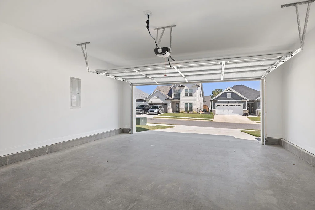 Empty garage with open door, concrete floor, and view of suburban homes, showcasing construction quality by Pratt Home Builders in Chattanooga TN.
