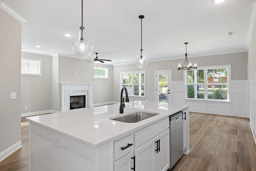 Modern open-concept kitchen and living area by Pratt Home Builders in Chattanooga TN, featuring an island, fireplace, and large windows.