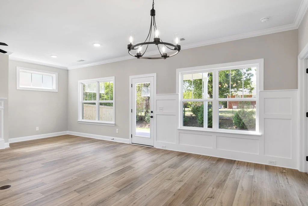 Bright, modern living space with wooden floors and large windows. Elegant chandelier lighting by Pratt Home Builders in Chattanooga TN.