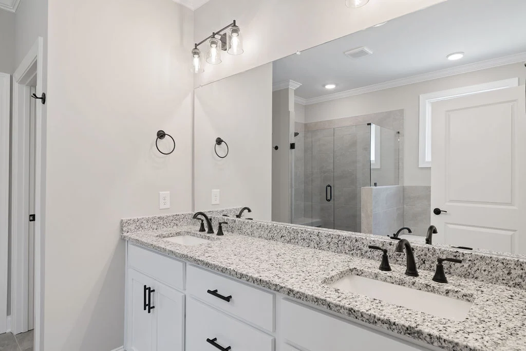 Elegant bathroom by Pratt Home Builders in Chattanooga TN, featuring dual sinks, granite countertops, and a glass-enclosed shower.