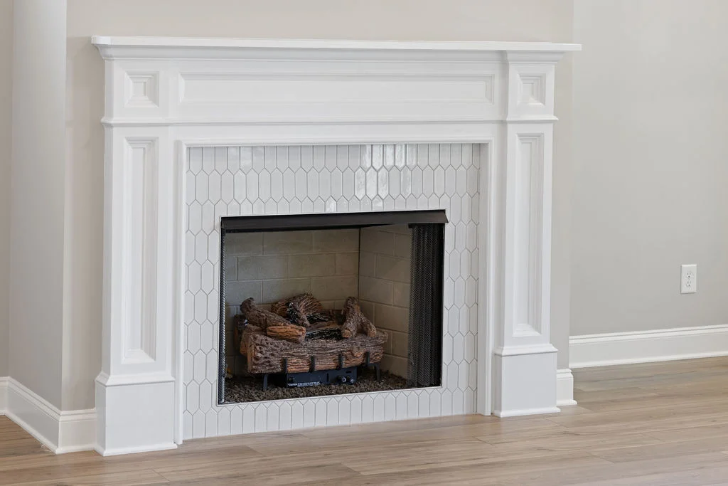 White fireplace with decorative hexagonal tiles, featuring a classic design by Pratt Home Builders in Chattanooga TN.