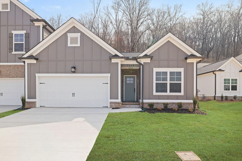Gray modern home with white garage and front door, nestled in a wooded area. Built by Pratt Home Builders in Chattanooga TN.
