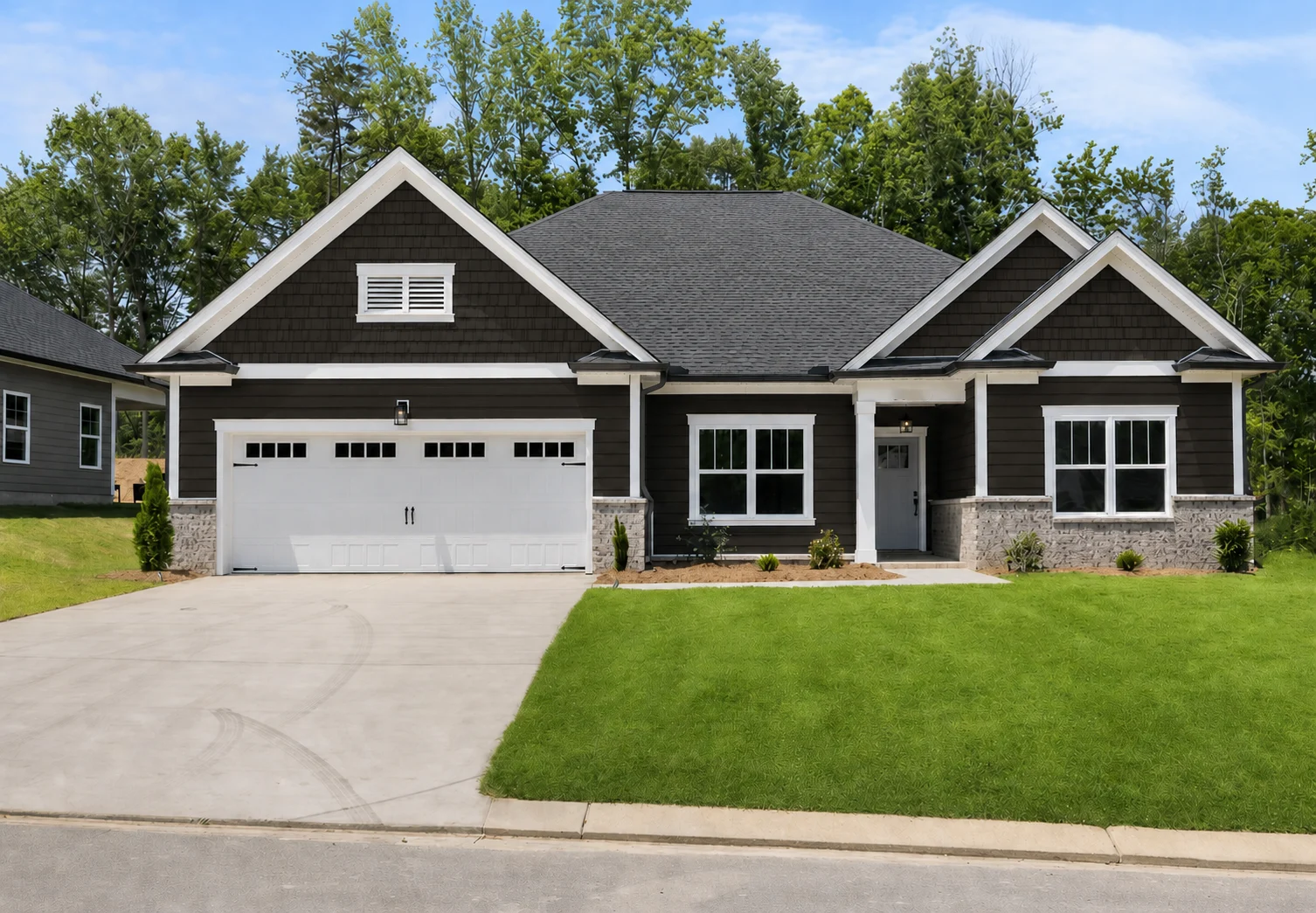 Single-story home by Pratt Home Builders in Chattanooga TN, featuring a dark facade, two-car garage, and manicured lawn, set against lush trees.