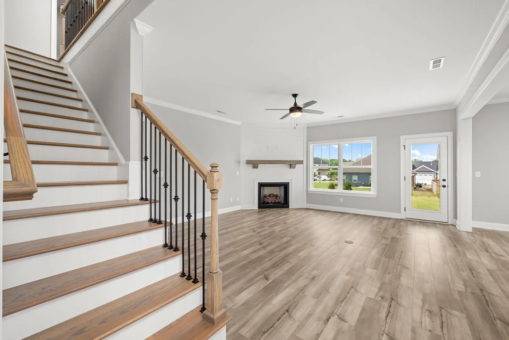 Spacious living room with wood flooring, natural light, staircase, fireplace, and ceiling fan. Built by Pratt Home Builders in Chattanooga TN.