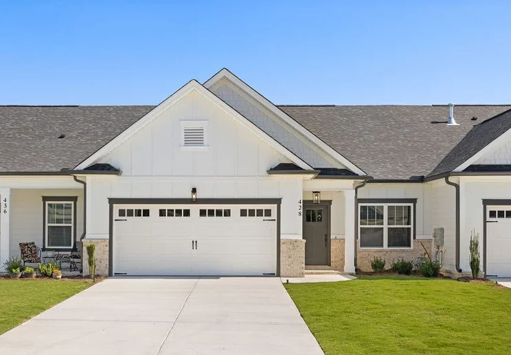 Modern townhouse with white facade, two garages, and neatly landscaped front yard by Pratt Home Builders in Chattanooga TN.