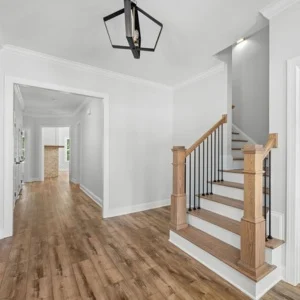 Bright hallway with wooden floors, modern staircase, and black pendant light. Crafted by Pratt Home Builders in Chattanooga TN.