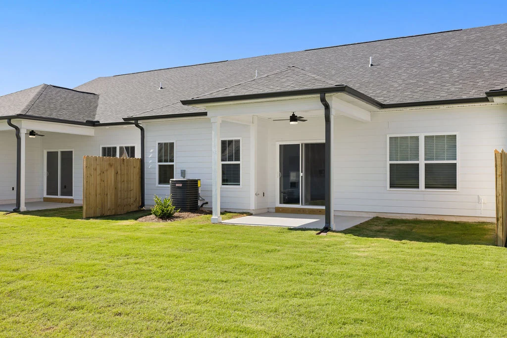 Spacious backyard with green lawn, white siding, and sliding glass doors by Pratt Home Builders in Chattanooga TN.