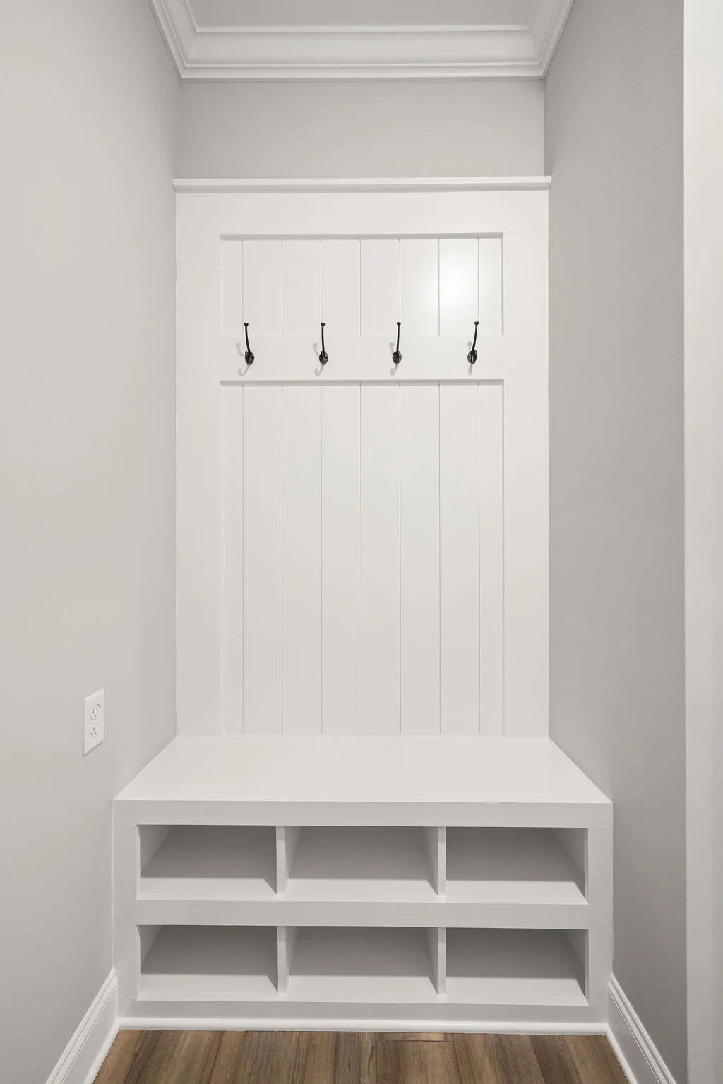 White mudroom bench with hooks and storage cubbies, showcasing Pratt Home Builders' craftsmanship in Chattanooga, TN.