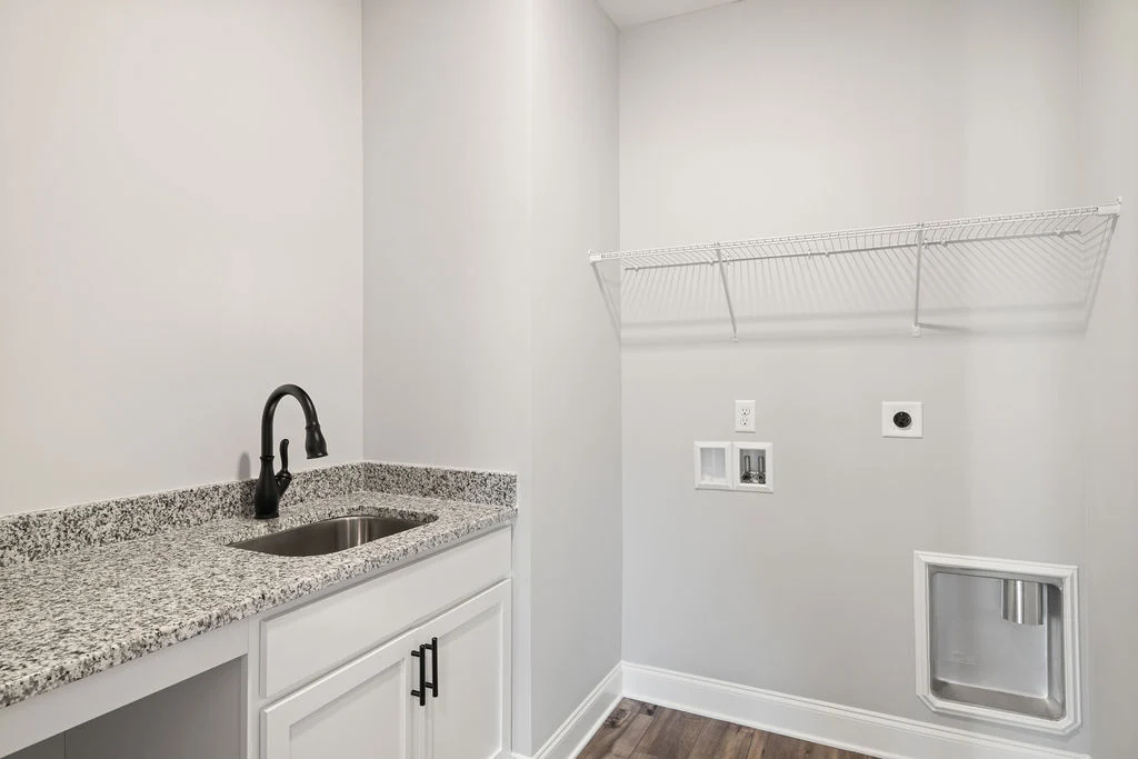 Laundry room by Pratt Home Builders in Chattanooga, TN, featuring a granite countertop, stainless steel sink, and wire shelf.