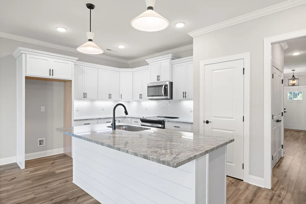 Modern kitchen by Pratt Home Builders in Chattanooga TN, featuring white cabinets, marble island, stainless steel appliances, and pendant lighting.