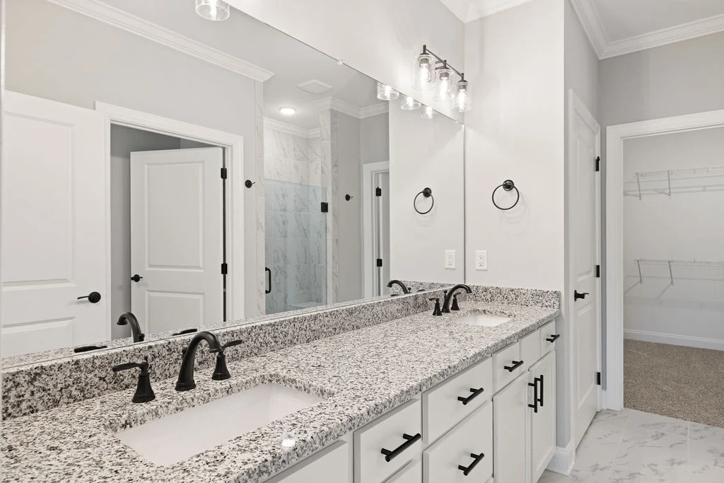 Modern bathroom with dual sinks, granite countertops, and black fixtures. Spacious, designed by Pratt Home Builders in Chattanooga TN.