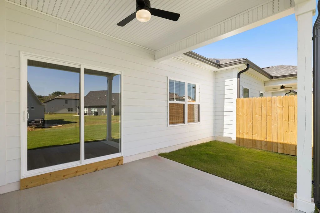 Covered patio with sliding glass doors, ceiling fan, and fenced yard. Built by Pratt Home Builders in Chattanooga TN.
