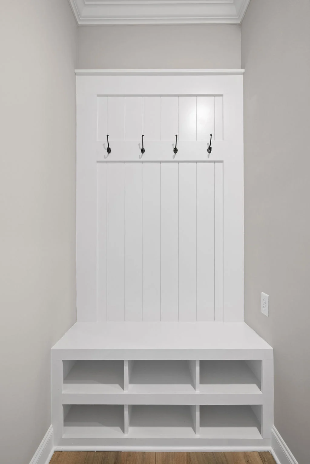White built-in mudroom bench with storage cubbies and coat hooks, designed by Pratt Home Builders in Chattanooga TN.