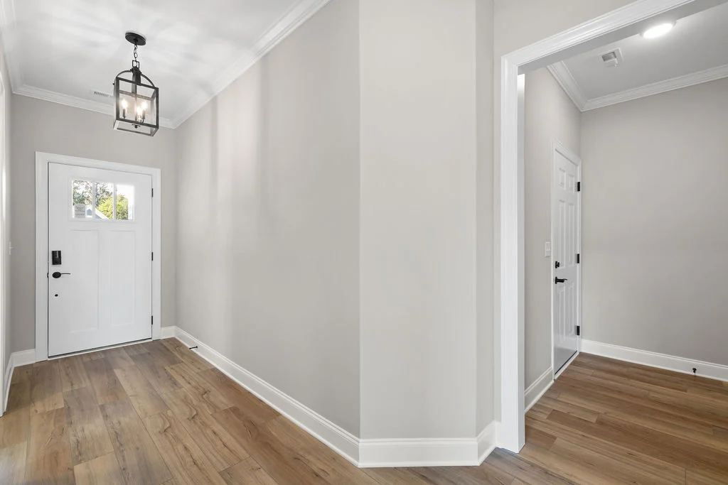Bright hallway with wooden floor, white front door, and modern lantern light. Pratt Home Builders in Chattanooga TN design.