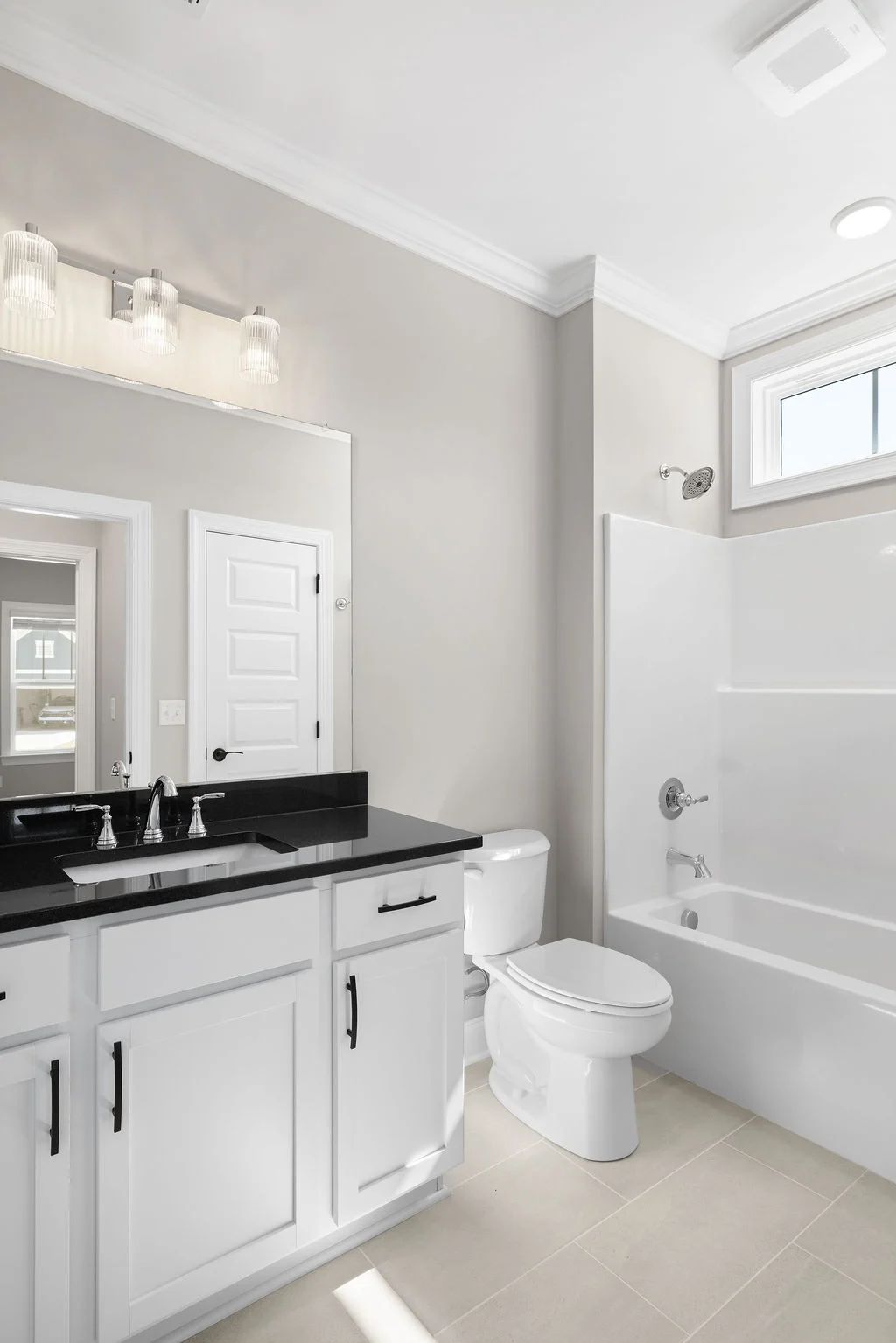 Modern bathroom with black countertop, white cabinets, and bathtub, designed by Pratt Home Builders in Chattanooga, TN.