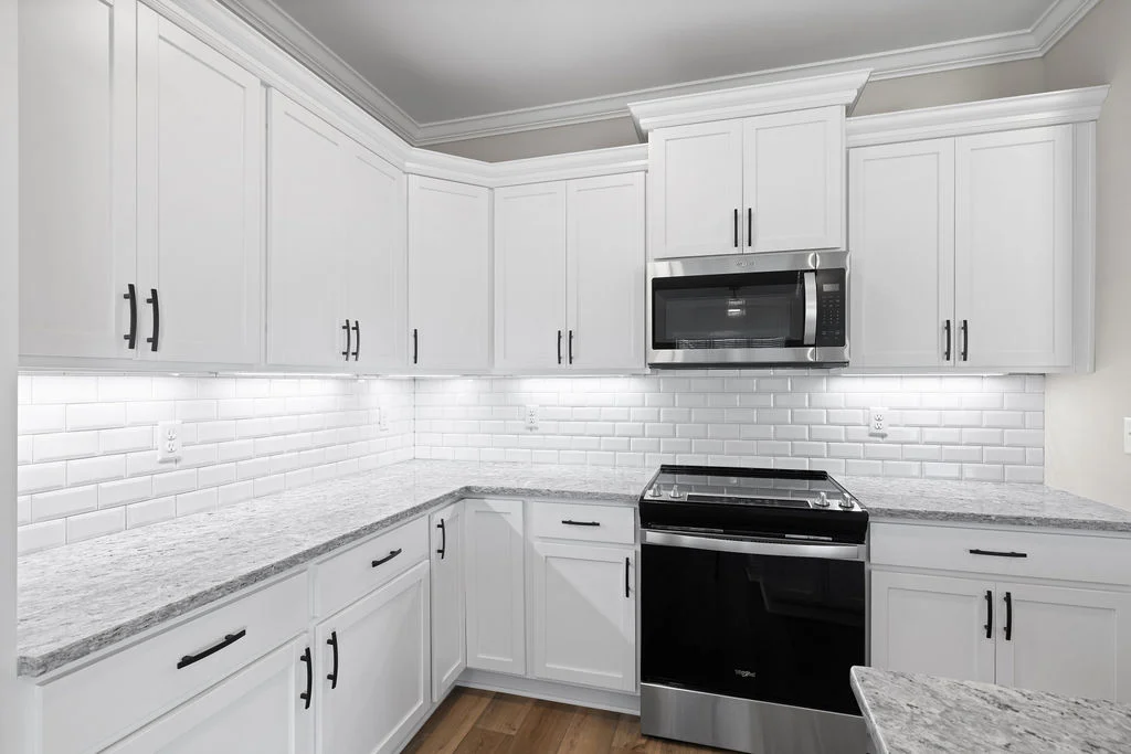 Modern kitchen with white cabinets, stainless steel appliances, subway tile backsplash, and granite countertops by Pratt Home Builders in Chattanooga