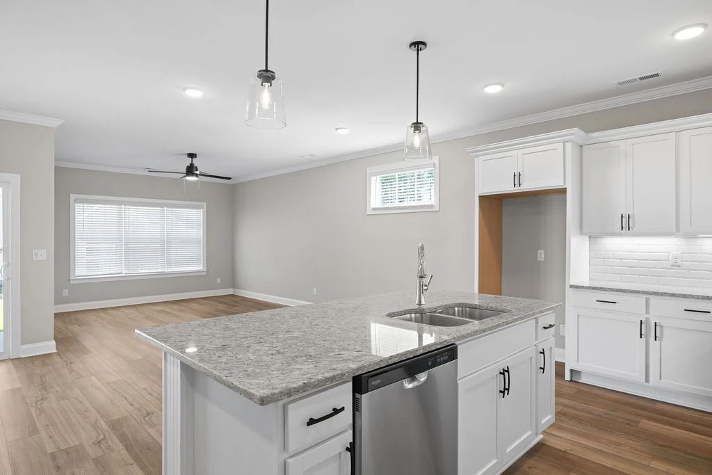 Modern kitchen by Pratt Home Builders in Chattanooga TN, featuring white cabinets, granite countertops, island with sink, and hardwood floors.