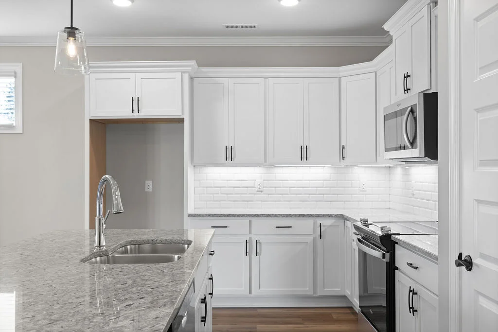 Modern kitchen with white cabinets, gray countertops, stainless steel appliances. Designed by Pratt Home Builders in Chattanooga, TN.